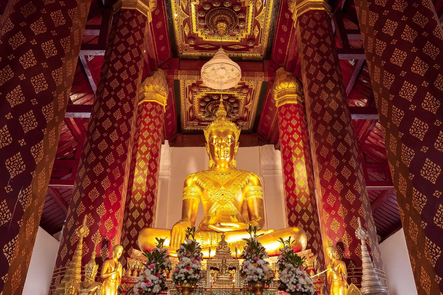พระพุทธนิมิตฯ พระประธานทรงเครื่องปางมารวิชัยองค์ใหญ่ปิดทอง ในพระอุโบสถวัดหน้าพระเมรุ ระหว่างเสาแปดเหลี่ยมสีแดงลายทอง