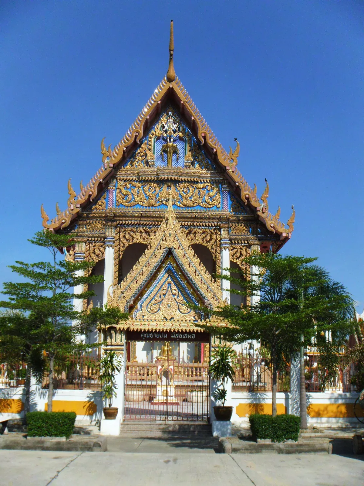 อุโบสถวัดราษฎร์บูรณะด้านหน้า หลังคาจั่วสูง หน้าบันสีน้ำเงินลายทอง มีมุขและซุ้มประตูด้านหน้า กำแพงแก้วสีขาวคาดเหลือง