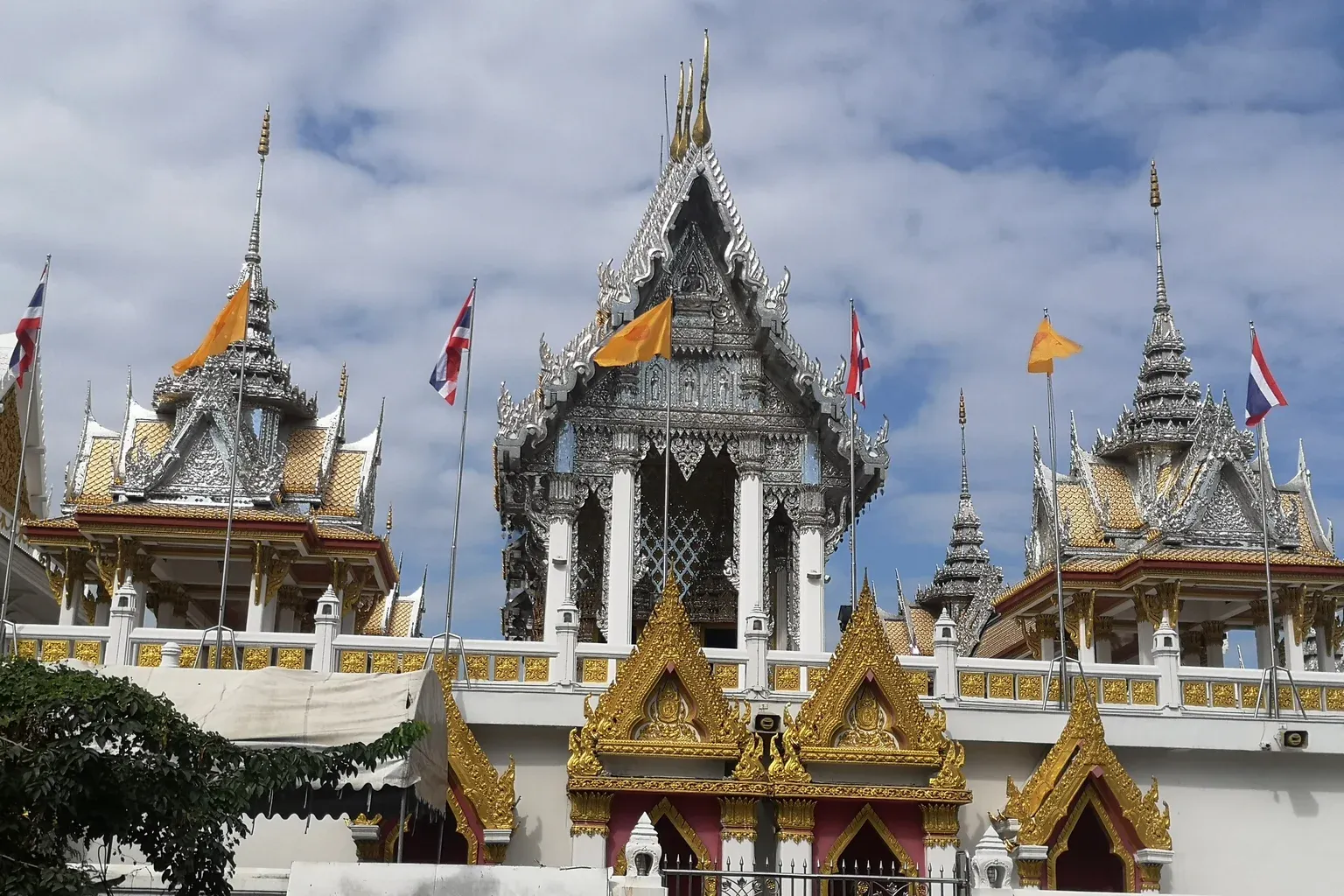 อุโบสถวัดศรีเอี่ยม หน้าบันสีเงิน เสาสีขาว ตั้งบนชั้นล่างผนังขาวที่มีซุ้มประตูสีทอง มีธงชาติและธงธรรมจักรบนระเบียง