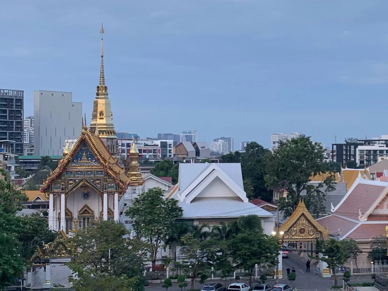 พระอุโบสถและเจดีย์ยอดสีทองของวัดธาตุทอง เอกมัย มีตึกสูงย่านสุขุมวิทอยู่ด้านหลัง
